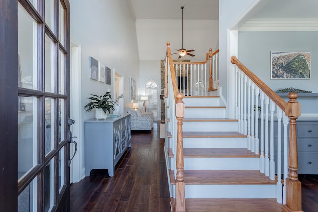 staircase featuring hardwood / wood-style flooring, ceiling fan, a towering ceiling, and ornamental molding