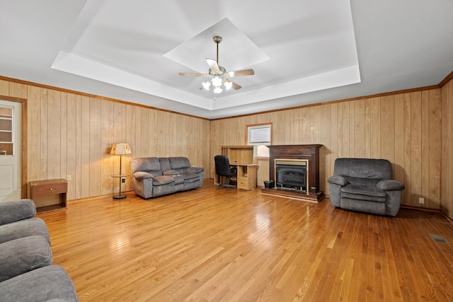 living room featuring wood walls, a raised ceiling, and hardwood / wood-style floors