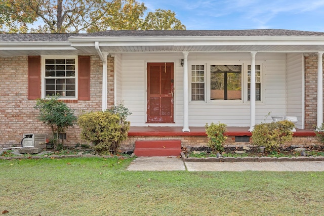 doorway to property featuring a lawn and a porch