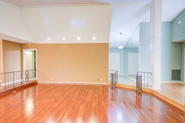 empty room with hardwood / wood-style flooring and high vaulted ceiling