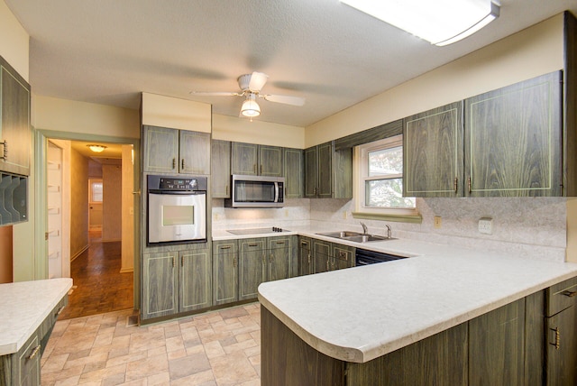 kitchen featuring kitchen peninsula, stainless steel appliances, sink, tasteful backsplash, and ceiling fan