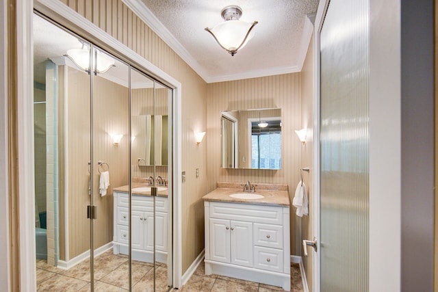 bathroom featuring vanity, a textured ceiling, ornamental molding, and tile patterned flooring