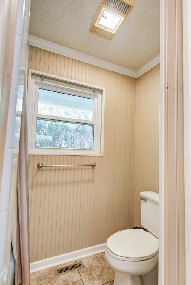 bathroom featuring toilet, crown molding, tile patterned floors, and a textured ceiling