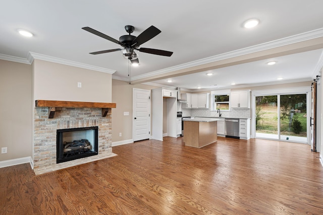 unfurnished living room with wood-type flooring, a brick fireplace, ceiling fan, and ornamental molding