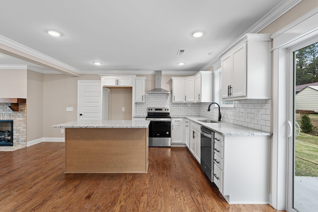 kitchen with appliances with stainless steel finishes, wall chimney exhaust hood, sink, a center island, and white cabinetry