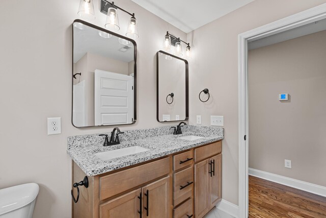 bathroom with hardwood / wood-style flooring, vanity, and toilet