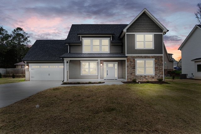 view of front of house featuring central AC, a yard, covered porch, and a garage