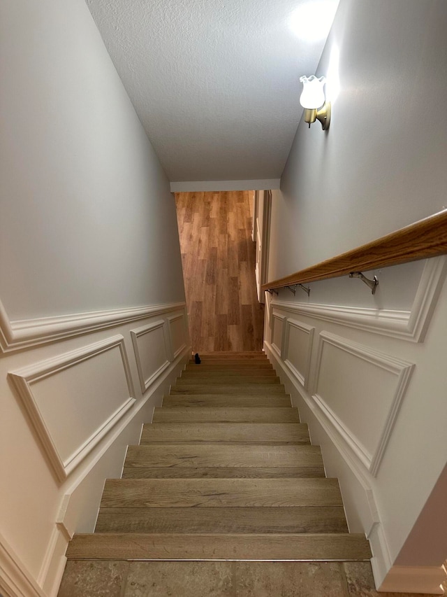 stairs with hardwood / wood-style floors and a textured ceiling