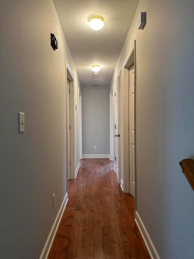 hall with dark wood-type flooring and a textured ceiling