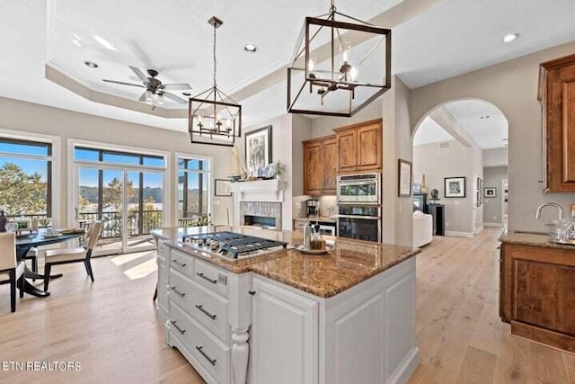 kitchen featuring a kitchen island, light hardwood / wood-style flooring, hanging light fixtures, white cabinetry, and light stone counters