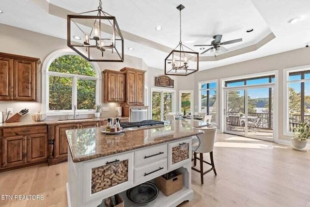 kitchen with sink, pendant lighting, light wood-type flooring, white cabinetry, and light stone counters