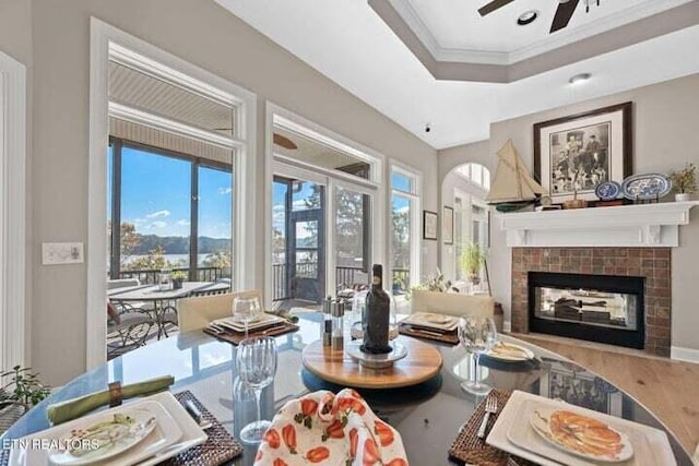 living room featuring crown molding, wood-type flooring, a tile fireplace, and ceiling fan