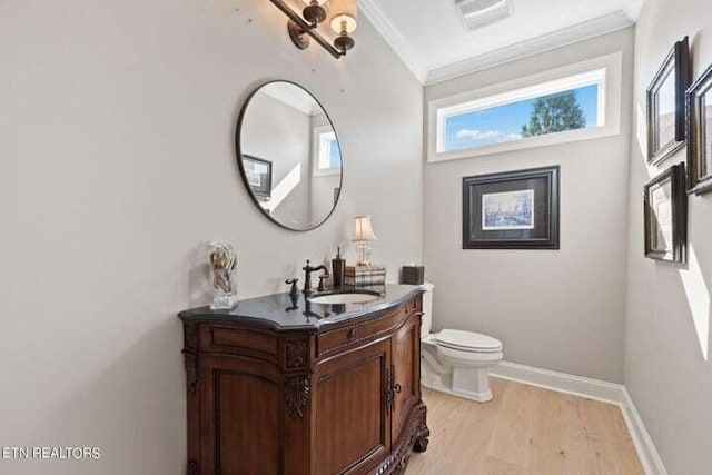 bathroom with vanity, wood-type flooring, ornamental molding, and toilet