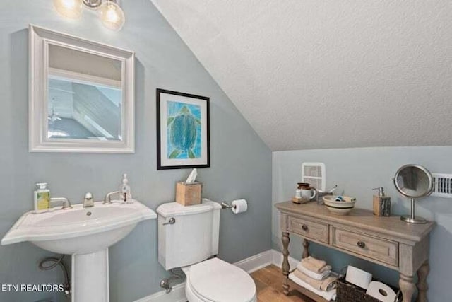 bathroom with lofted ceiling, wood-type flooring, a textured ceiling, and toilet