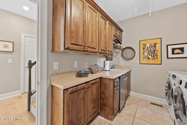 kitchen featuring sink, light tile patterned flooring, separate washer and dryer, and dishwasher