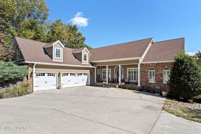 new england style home featuring covered porch and a garage