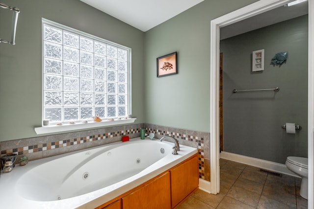 bathroom with a washtub, tile patterned floors, and toilet