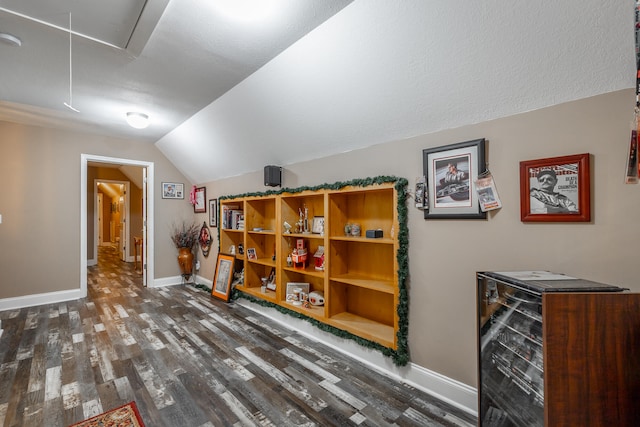 bonus room featuring lofted ceiling, beverage cooler, and dark hardwood / wood-style floors