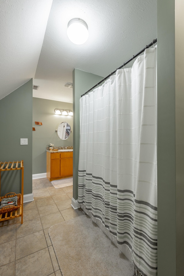 bathroom featuring vanity, tile patterned floors, and lofted ceiling