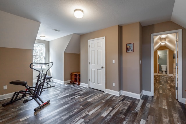 workout room featuring a textured ceiling, dark wood-type flooring, and lofted ceiling