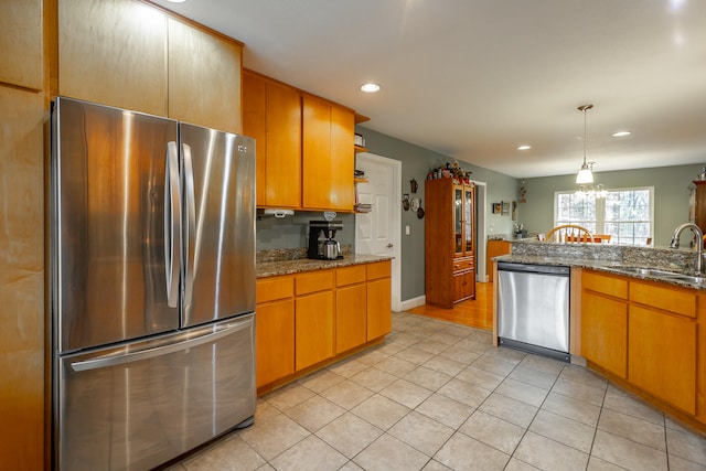 kitchen with sink, light tile patterned floors, dark stone counters, and appliances with stainless steel finishes