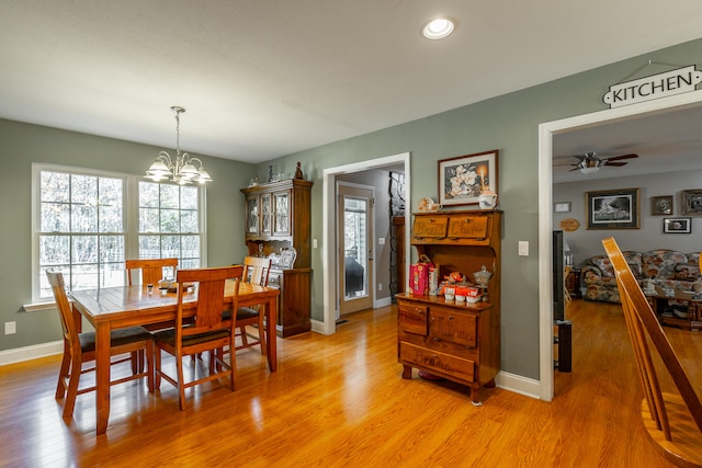 dining area with ceiling fan with notable chandelier and light wood-type flooring