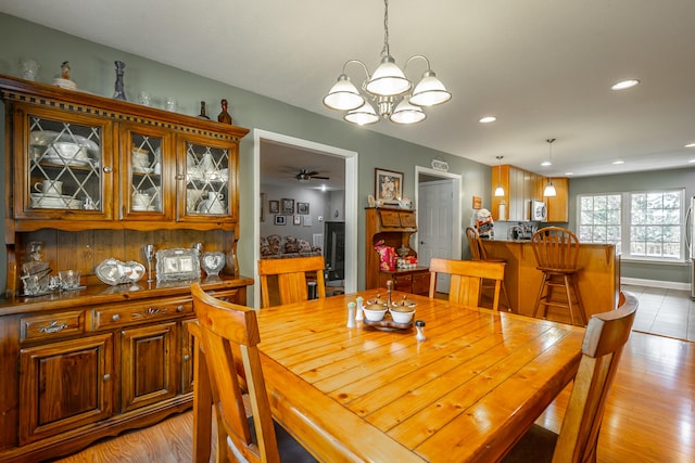 dining room with light hardwood / wood-style flooring and ceiling fan with notable chandelier