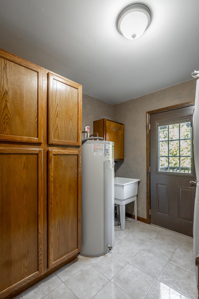 washroom with sink, gas water heater, light tile patterned floors, and cabinets