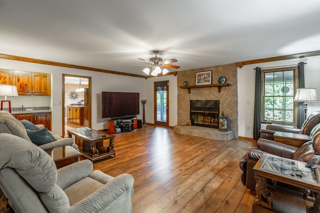 living room with sink, a fireplace, hardwood / wood-style floors, ceiling fan, and crown molding