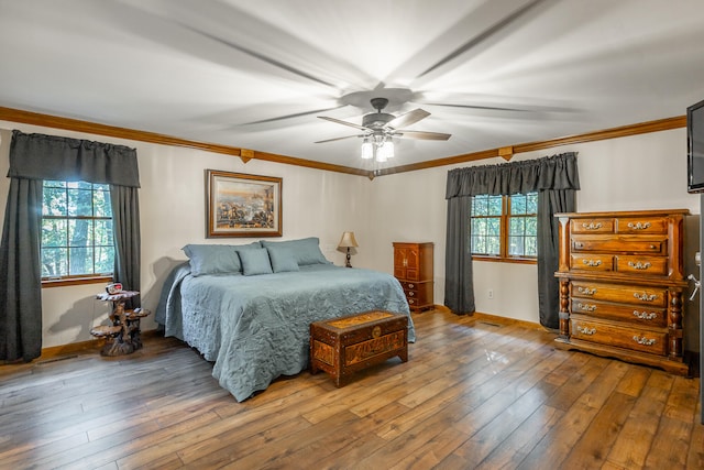 bedroom with ornamental molding, multiple windows, hardwood / wood-style floors, and ceiling fan