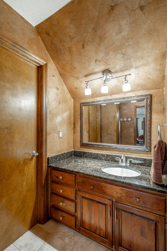 bathroom featuring vanity, vaulted ceiling, and tile patterned flooring