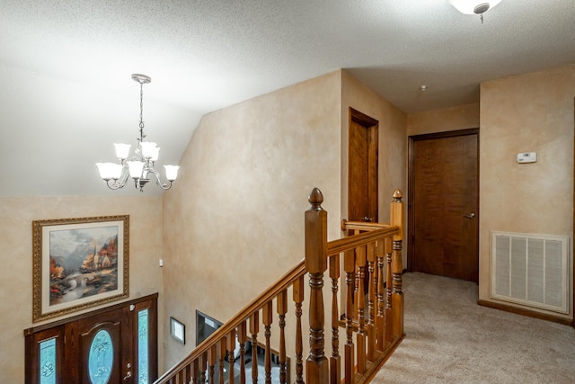 hall with light carpet, a textured ceiling, a chandelier, and vaulted ceiling