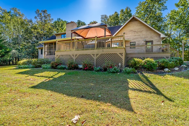 rear view of property featuring a yard, a deck, and a sunroom