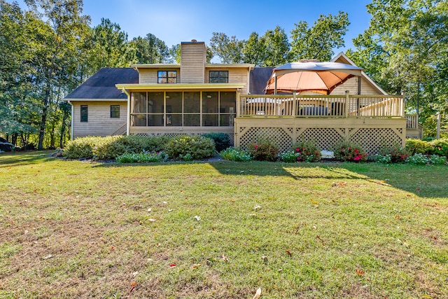 back of house with a deck, a sunroom, and a lawn