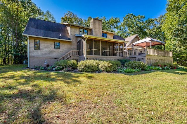 back of property with a sunroom, a deck, and a lawn