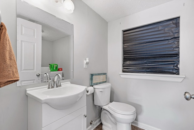 bathroom featuring vanity, a textured ceiling, and toilet