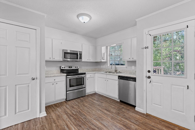 kitchen with dark hardwood / wood-style floors, ornamental molding, white cabinets, appliances with stainless steel finishes, and a textured ceiling