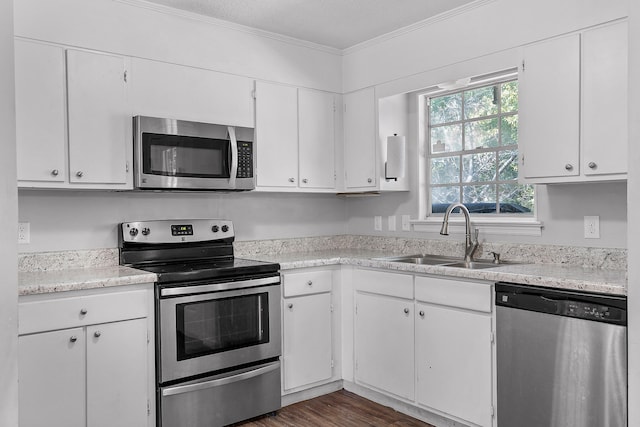 kitchen with ornamental molding, sink, appliances with stainless steel finishes, and white cabinets