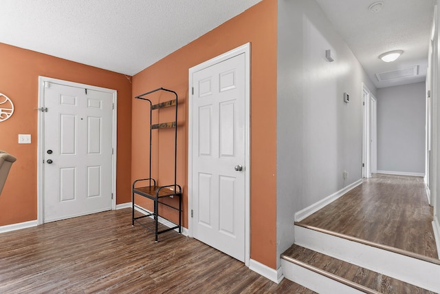 entryway with dark wood-type flooring and a textured ceiling