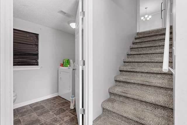 stairway featuring washer / dryer, a textured ceiling, and an inviting chandelier