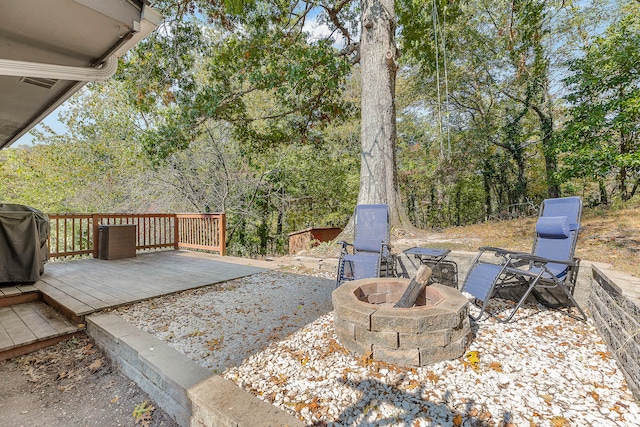 exterior space featuring a wooden deck, an outdoor fire pit, and a grill