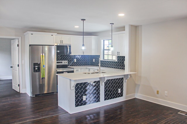 kitchen with sink, appliances with stainless steel finishes, pendant lighting, and dark hardwood / wood-style flooring