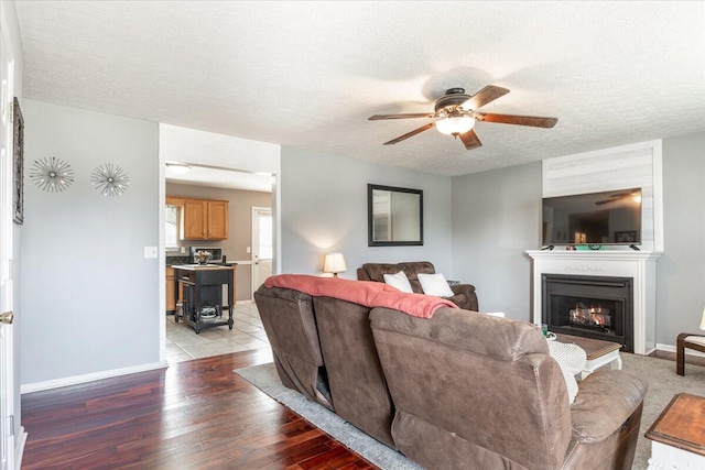 living room featuring ceiling fan, wood-type flooring, and a textured ceiling