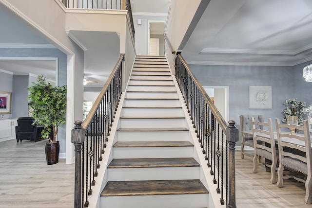 staircase featuring a notable chandelier, wood-type flooring, and crown molding