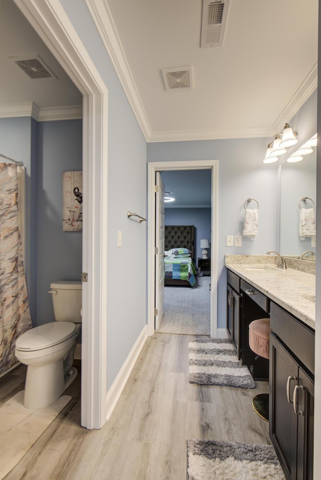 bathroom with wood-type flooring, vanity, toilet, and ornamental molding