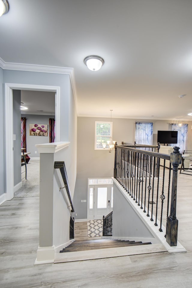 staircase with hardwood / wood-style flooring, ornamental molding, and a chandelier