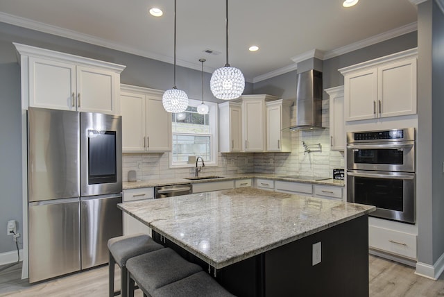 kitchen featuring sink, a center island, wall chimney range hood, a kitchen breakfast bar, and appliances with stainless steel finishes