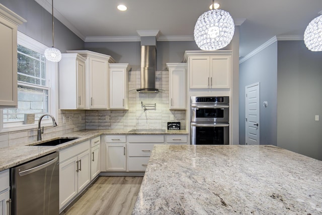 kitchen featuring sink, wall chimney exhaust hood, stainless steel appliances, and a notable chandelier