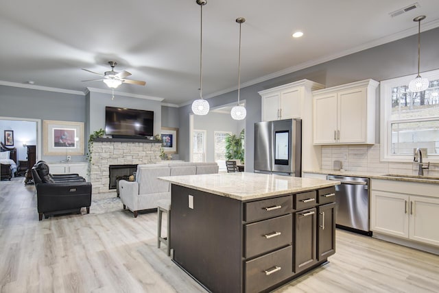 kitchen featuring ceiling fan with notable chandelier, sink, a fireplace, white cabinetry, and stainless steel appliances