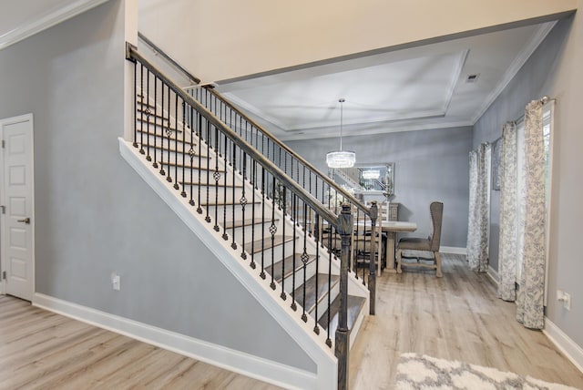 staircase featuring a chandelier, wood-type flooring, and crown molding